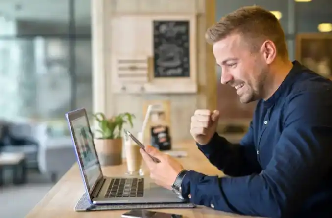 Empresario celebrando frente a su laptop tras mejorar la visibilidad digital de su PYME en Internet.