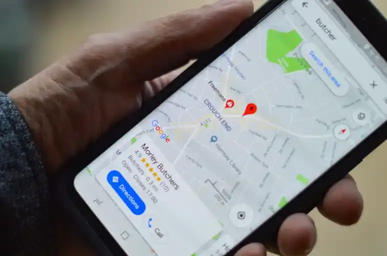 Mano de una persona mostrando en su smartphone un mapa de Google Maps con marcadores de ubicación, destacando cómo se utiliza la app para encontrar negocios locales.