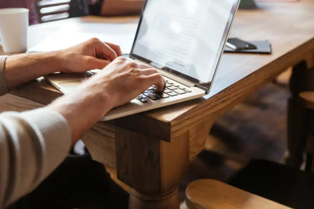 Manos escribiendo en laptop mientras se analiza la diferencia entre copywriting vs UX writing en marketing digital.